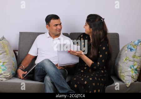 Young Indian couple discussing with documents on sofa. Stock Photo