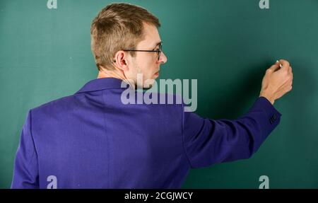 Teacher write on chalkboard rear view, making notes concept. Stock Photo