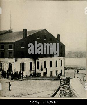 . The Photographic history of the Civil War : thousands of scenes photographed 1861-65, with text by many special authorities . LIBBY PRISON AFTER THE TABLES WERE TURNED In this dramatic record by the camera of April, 1805, appear Confederate captives pressing their faces against the bars through whichone hundred and twenty-five thousand Federal prisoners had gazed from the inside during the war. Union sentinels are guardingthe prison. Major Thomas P. Turner, who had been commandant of the prison, though a subordinate, Richard Turner, had moredirect authority, was confined here at this time. S Stock Photo