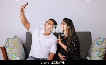 indian young Couple taking a self portrait or selfie using smart-phone. Stock Photo