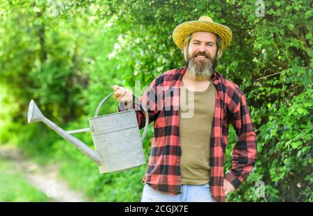 plant nursery. Gardener pouring water from can. mature agricultural worker with watering can. caucasian male farmer in country. Gardening in vegetable garden. watering plants and flowers. Stock Photo