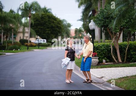 Elderly retierment couple holding hands and laughing in a street Stock Photo