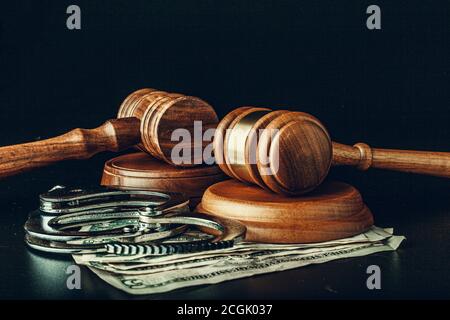 Bribe concept. Dollar banknotes, handcuffs and gavel on dark black table Stock Photo