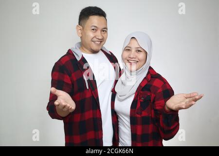 Beautiful happy Asian muslim couple wearing casual clothes smiling friendly offering handshake as greeting and welcoming Stock Photo