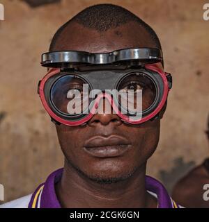 Portrait of adolescent  young African man, wearing weldering protection goggles, with background outside Stock Photo