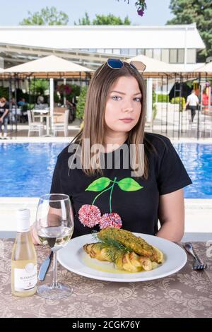 Woman eating main dish by the pool Stock Photo