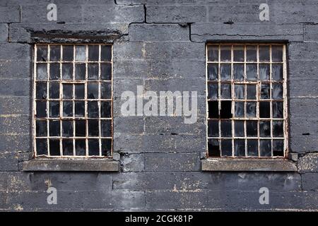 Old broken multi pane crittall windows and breeze block cinder block wall Stock Photo