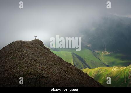 A man on top of a hill against the background of a green gorge with a thick cloud Stock Photo