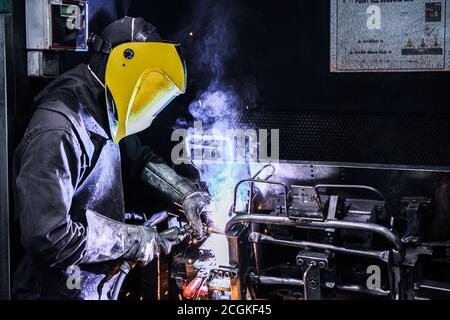 Man Welding on Assembly Line in Automotive Factory . Stock Photo