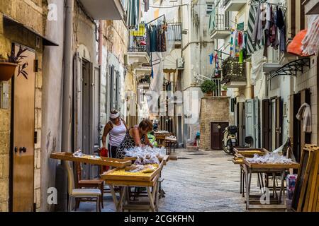 BARI, ITALY - SEPTEMBER 1, 2020: housewives making orecchiette in the streets of Bari Vecchia Stock Photo