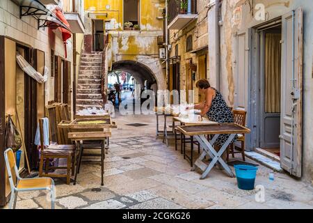 BARI, ITALY - SEPTEMBER 1, 2020: housewives making orecchiette in the streets of Bari Vecchia Stock Photo