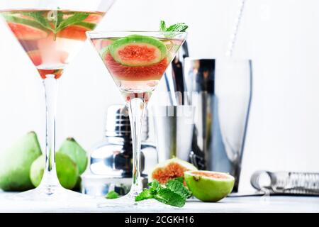 Pink fig martini cocktail in shot glass on gray table with bar tools, selective focus Stock Photo
