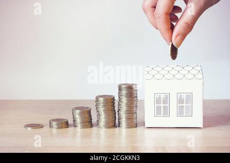 Close up of people hand, mini home and money,coins in home banking and saving concept. Idea Home finances, building savings and realty financing inves Stock Photo