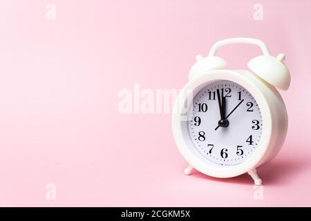White alarm clock on pink background, copy space. Minimalistic background, concept of time, deadline, time to work, morning Stock Photo