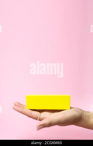 Business concept growth success process, Cropped view of Woman hand holding yellow block on paper pink background, copy space Stock Photo