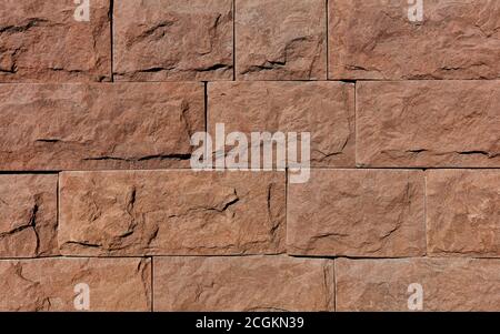 Wall background and texture of brown granite tiles with chips around the perimeter, close-up. Stock Photo