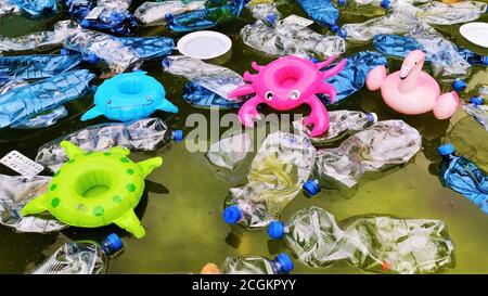 pollution of the environment. plastic bottles in water and inflatable toys.  Inflatable pink flamingos, green turtle, blue fish, raspberry crayfish am Stock Photo