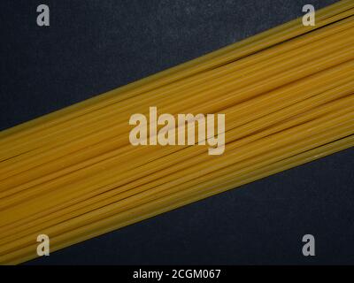 Raw spaghetti. Pasta arranged in a geometric pattern on a black background. Menu concept. Background for text. Stock Photo