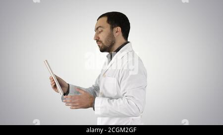 Young Doctor Video Chatting On Tablet on gradient background. Stock Photo