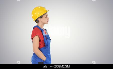 Construction worker lady walking emotionless on gradient backgro Stock Photo
