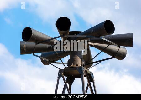 Old multidirectional emergency siren attached to a steel pylon. Concepts of urgent crisis communication, alarm and danger Stock Photo