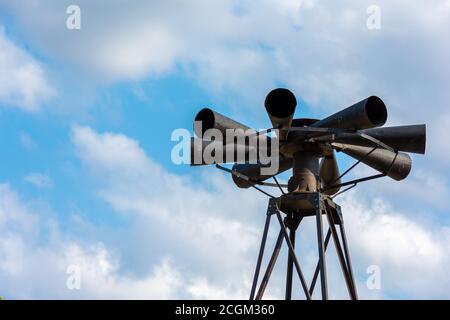 Old multidirectional emergency siren attached to a steel pylon. Concepts of urgent crisis communication, alarm and danger Stock Photo