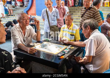 Chinatown, Singapore - 11 2018: Old men playing Xiangqi, chinese chess Stock Photo