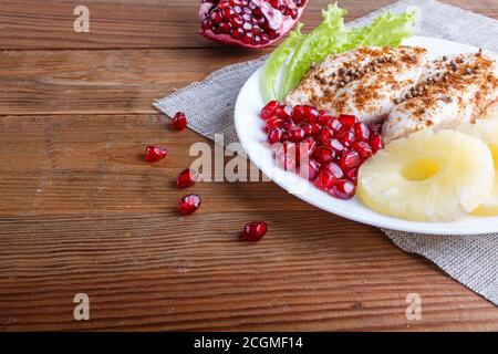 Fried chicken fillets with lettuce, pineapple and pomegranate seeds on brown wooden background, copy space, close up. Stock Photo