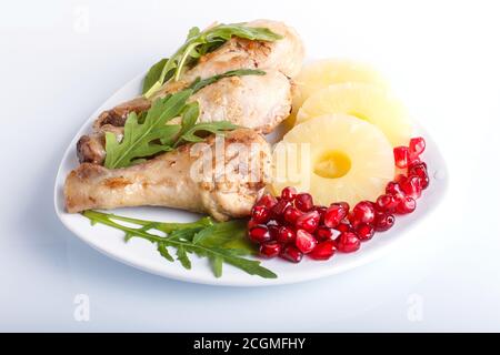 Fried chicken legs with rucola, pineapple and pomegranate seeds isolated on white background, close up. Stock Photo