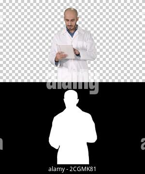 Mature male doctor holding digital tablet using it and walking, Stock Photo