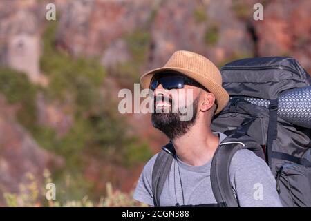 Hispanic male trekker with sunglasses smiling and admiring nature Stock Photo