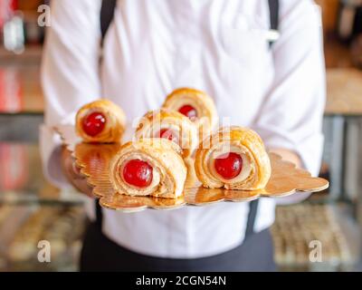 Cannoli with sour cherries served by girl, Bakery Stock Photo