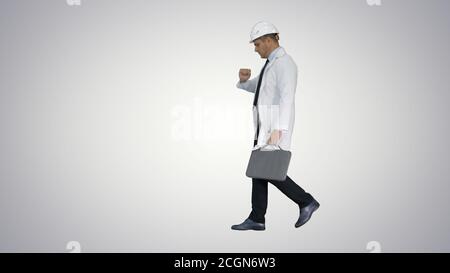 Engineer walking in a rush and looking at his watch on gradient Stock Photo