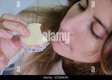 cute caucasian woman eating cornstarch alfajor with dulce de leche and drinking yerba mate infusion tea Stock Photo