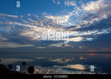 An abstract image taken at a lakefront at sunset. Image shows a spectacular cloudy sky and its reflection over water. Sky and water are separated only