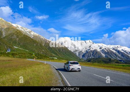 Cars run on highways in the morning with blue skies and clouds in summer. There are green grass beside the roads in Mount Cook National Park, Aoraki, Stock Photo