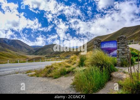 Beautiful valleys and hills in summer season with green grass at the Lindis Pass Summit scenic view out in Otago, New Zealand. Stock Photo