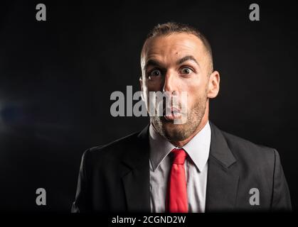 Surprised man in suit. Black background, close up. Stock Photo