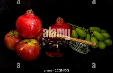 Honey, pomegranate, and apples on the black table. Jewish New Year Rosh Hashanah postcard. Stock Photo