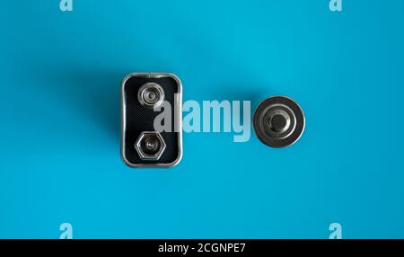 High voltage Volt 9V battery and alkaline AA battery on a blue background. Energy. Stock Photo