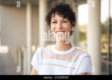 Close up portrait of smiling mature woman with short curly in city Stock Photo