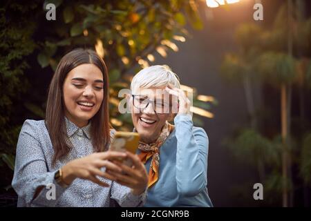 beautiful young woman showing content on her cell phone to her mother Stock Photo