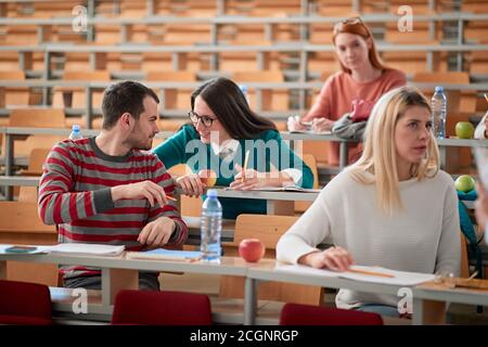 Students chatting at a lecture in an amphitheatre Stock Photo