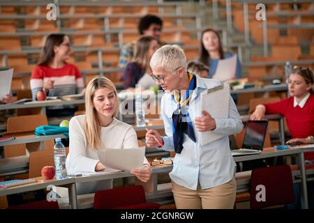 Female professor explaining the score of the exam to a female student in an amphitheatre Stock Photo