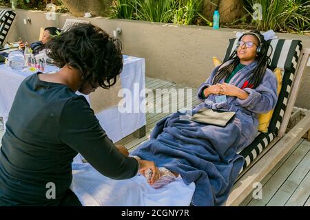 Johannesburg, South Africa - May 10, 2018: Diverse women in bath robes receiving a pedicure at spa resort Stock Photo