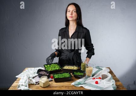 Picture of packing microgreens in containers by woman in black clothes Stock Photo