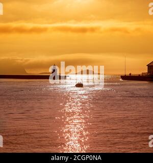 Harbour entrance Alesund with lighthouse Molja fyr, Alesund fyrstasjon, silhouettes in the evening, back light, Alesund, More og Romsdal, Norway Stock Photo