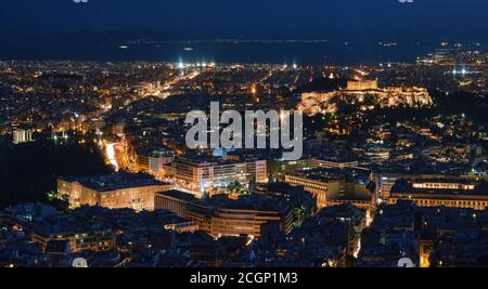 Panoramic night view of Athens and Acropolis, Parthenon and Erechtheion lit up by superb night lights. Saronic Gulf in background, Hellenic Parliament Stock Photo