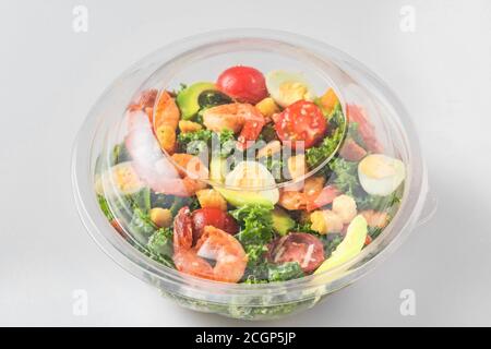 Plastic package with healthy shrimp caesar salad with avocado , kale, tomatoes and eggs to take away. close up. mediterranean diet Stock Photo