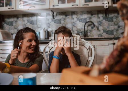 A beautiful caucasian mother and two sons are smeared with chocolate cream on their faces. Fun with kids Stock Photo